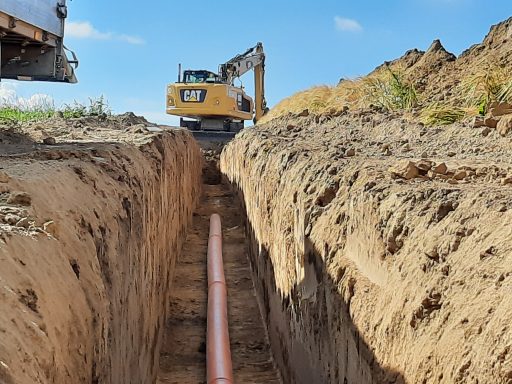 Graben mit Kanalrohr und Bagger