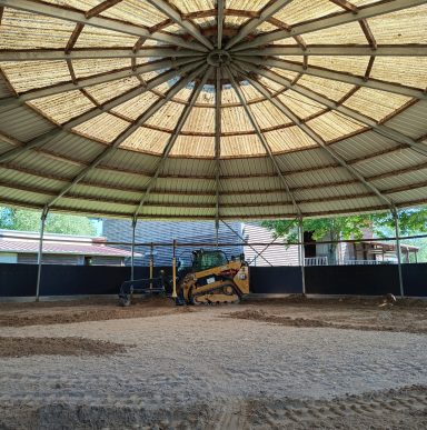 Roundpen überdacht mit einem Deltalader der Firma Cat beim planieren der Fläsche